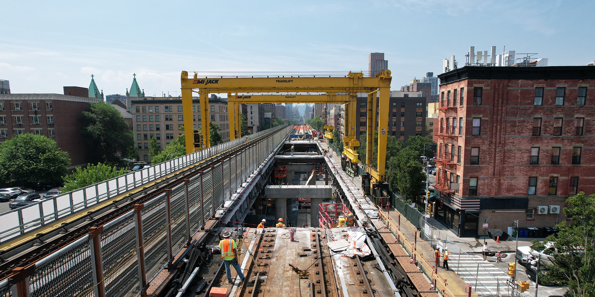 image of train tracks with construction work on top, buildings on both sides