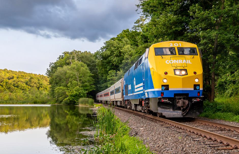 P32AC-DM No. 201 in Conrail heritage livery travels northbound on the Danbury Branch past Umpawaug Pond in Redding, Connecticut.