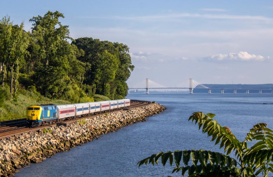 Penn Central heritage locomotive P32AC-DM No. 217 shoves a southbound Hudson Line train through Scarborough, New York, on a gorgeous summer afternoon in 2025, adding a flash of classic railroad history to the riverfront scenery.