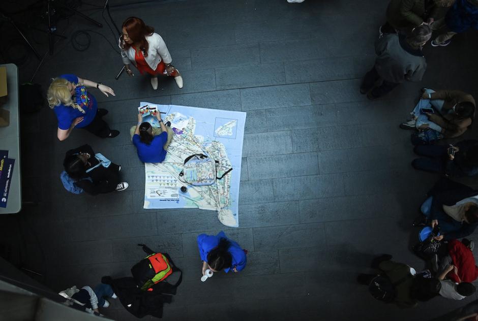 A group of people in a subway station uses a subway map for a demonstration.