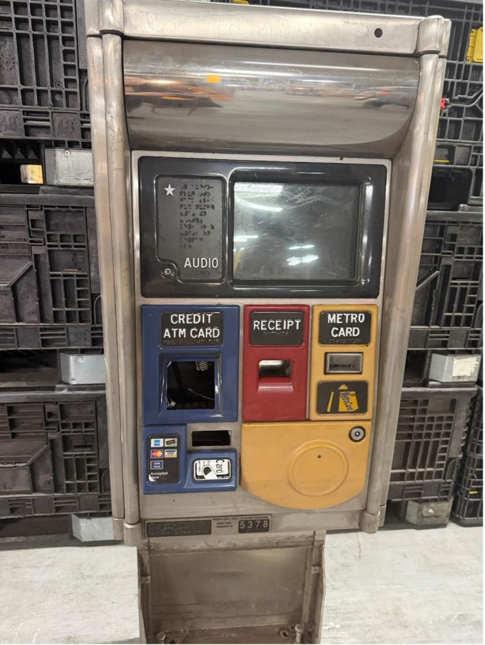 A silver metal MEM with it's screen off, with blue, red, and yellow plastic showing where cards can be purchased.
