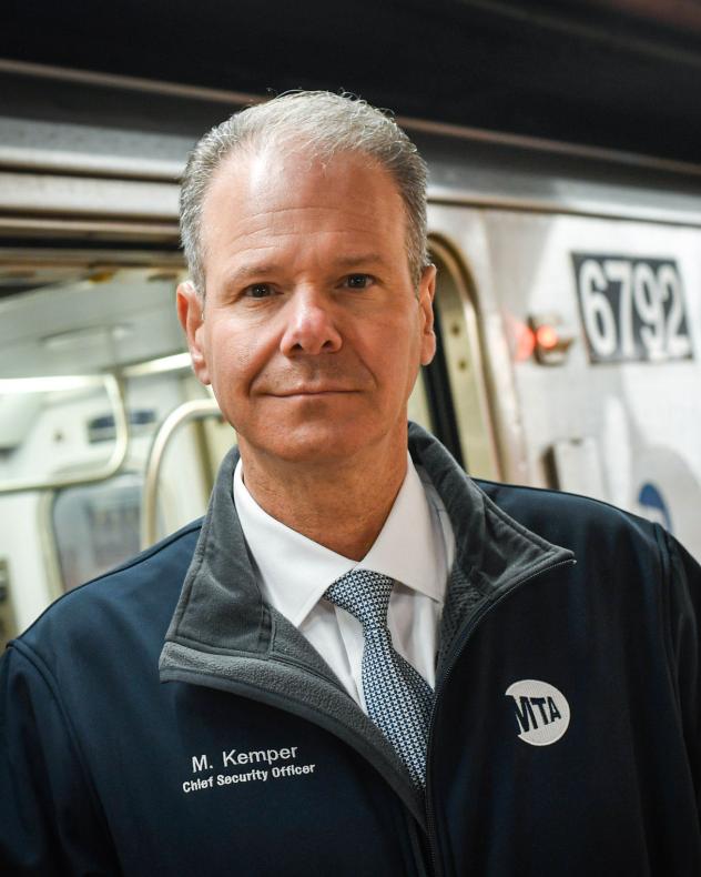 Michael Kemper wearing a dark jacket in front of a subway train