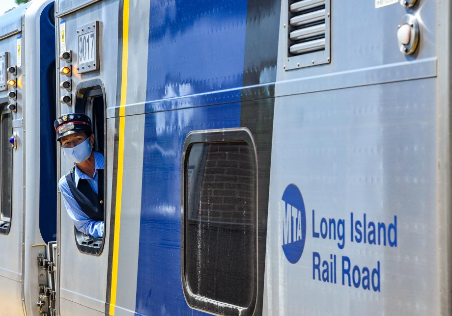 A train conductor leans out of a train car. 