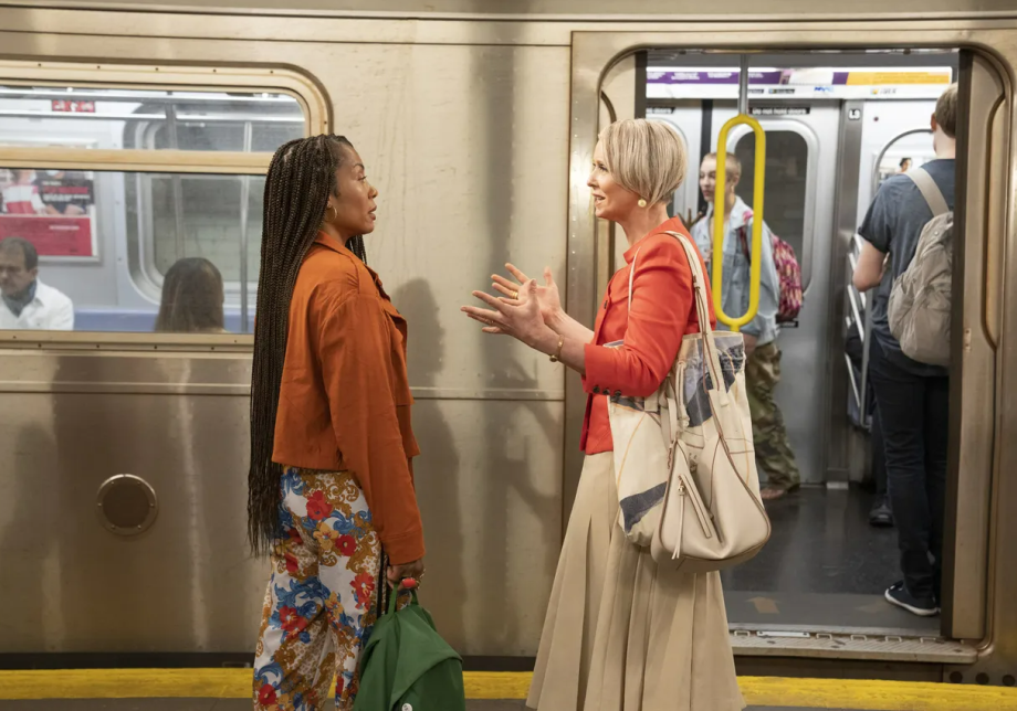 Karyn Pittman and Cynthia Nixon stand on a subway platform, in front of a train car