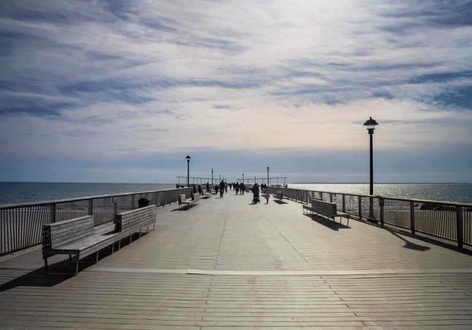 A boardwalk pier extending out into the Atlantic Ocean during daytime. 