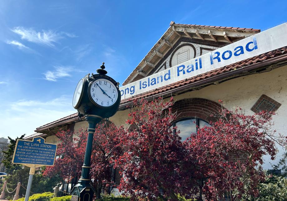 A train station building. There is a sign on the building that says "Long Island Rail Road." There is also a historic clock next to the building. 