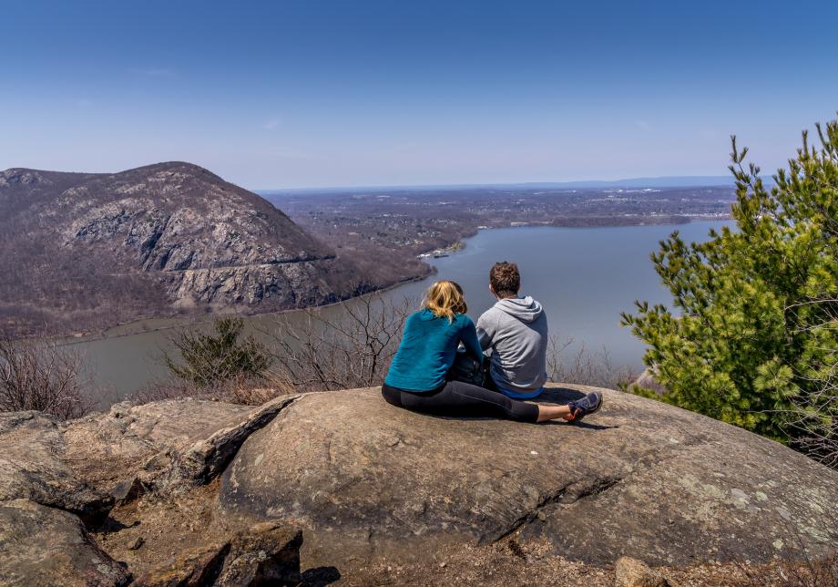 A young woman and man sit on top of Bull Hill, a mountain in New York state. 