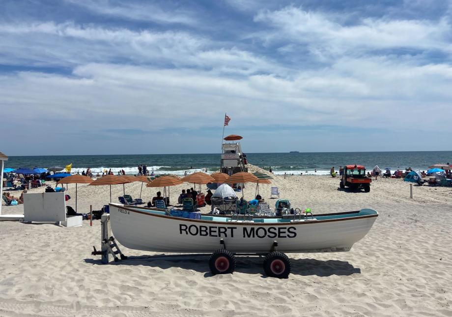 A boat on a beach. The boat has the words "Robert Moses" printed on it. 