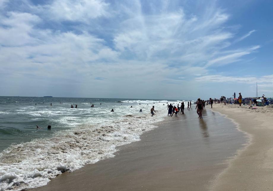 People on a beach with blue skies and clouds overhead.