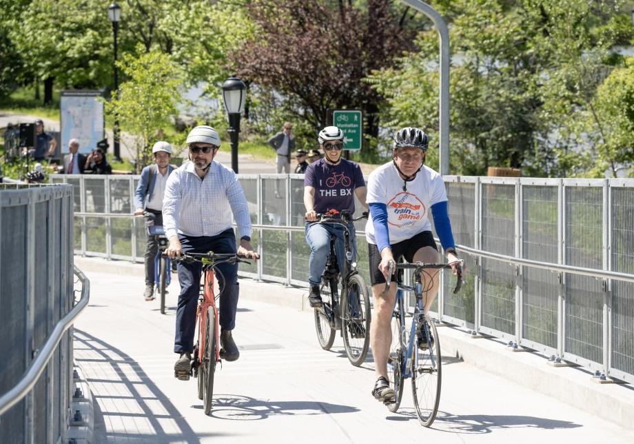 Three people on bicycles ride on a bike path on a bridge. 