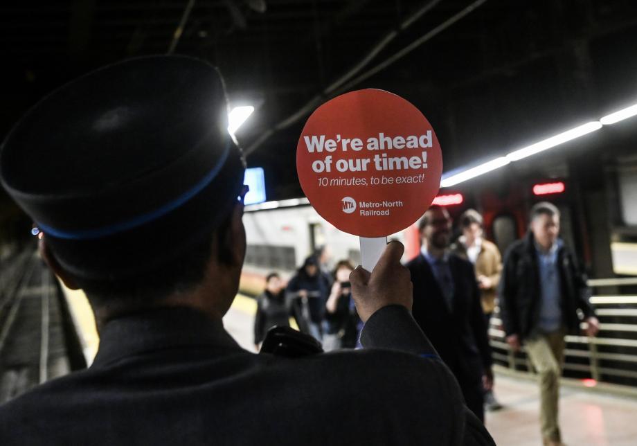 A train conductor holding a sign that says "We're ahead of our time! 10 minutes to be exact"