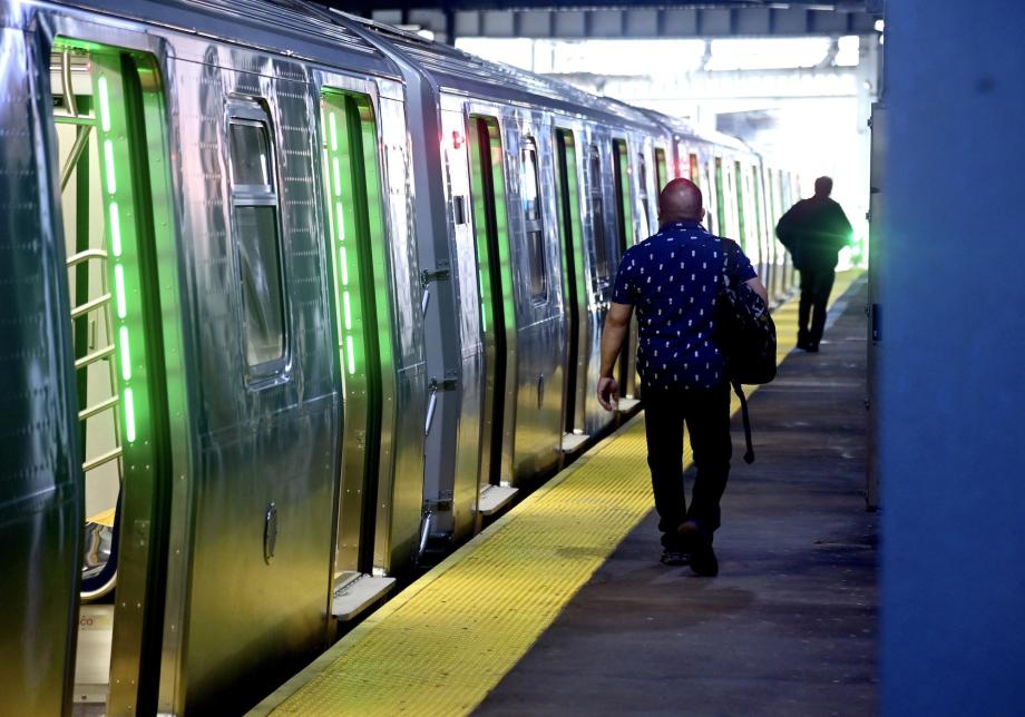 People walking on a subway platform next to a train car. 