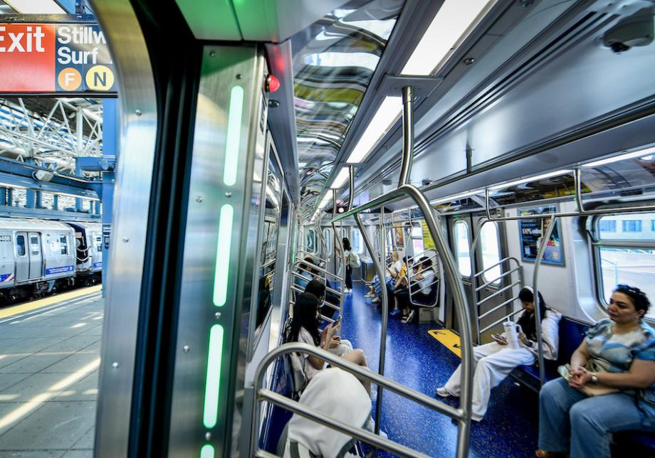 People sit on benches inside a new subway car. 