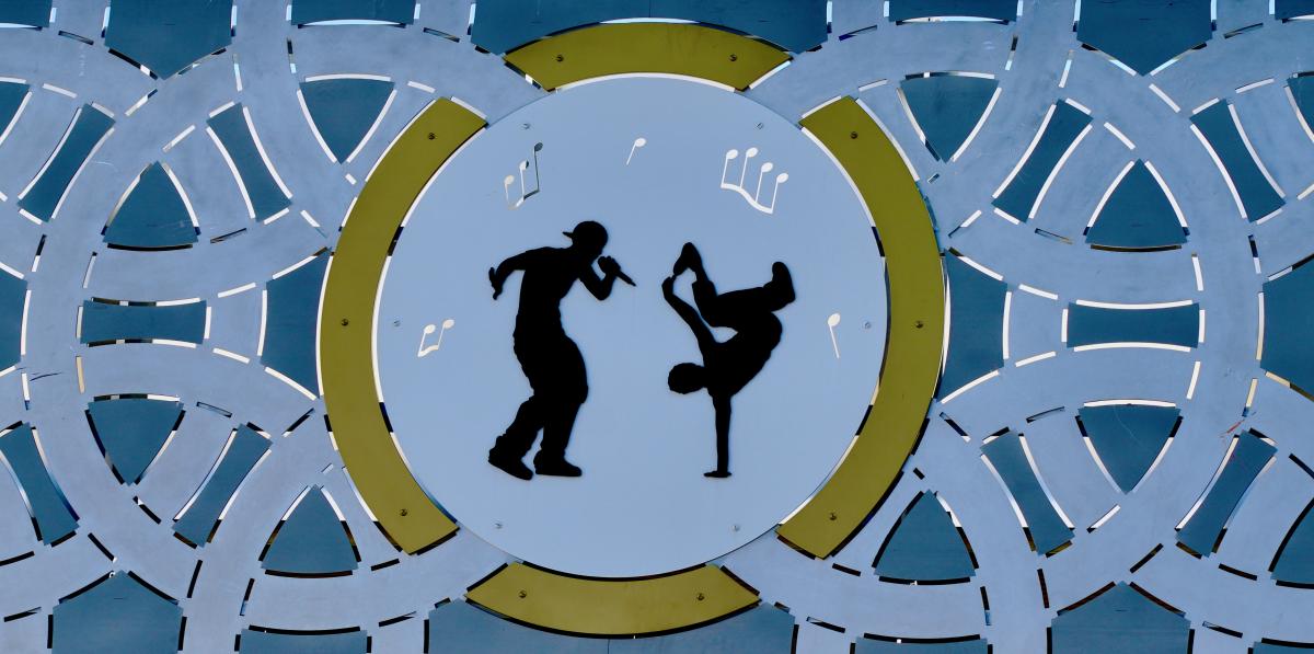 Detail of metal artwork showing silhouetted figures dancing.