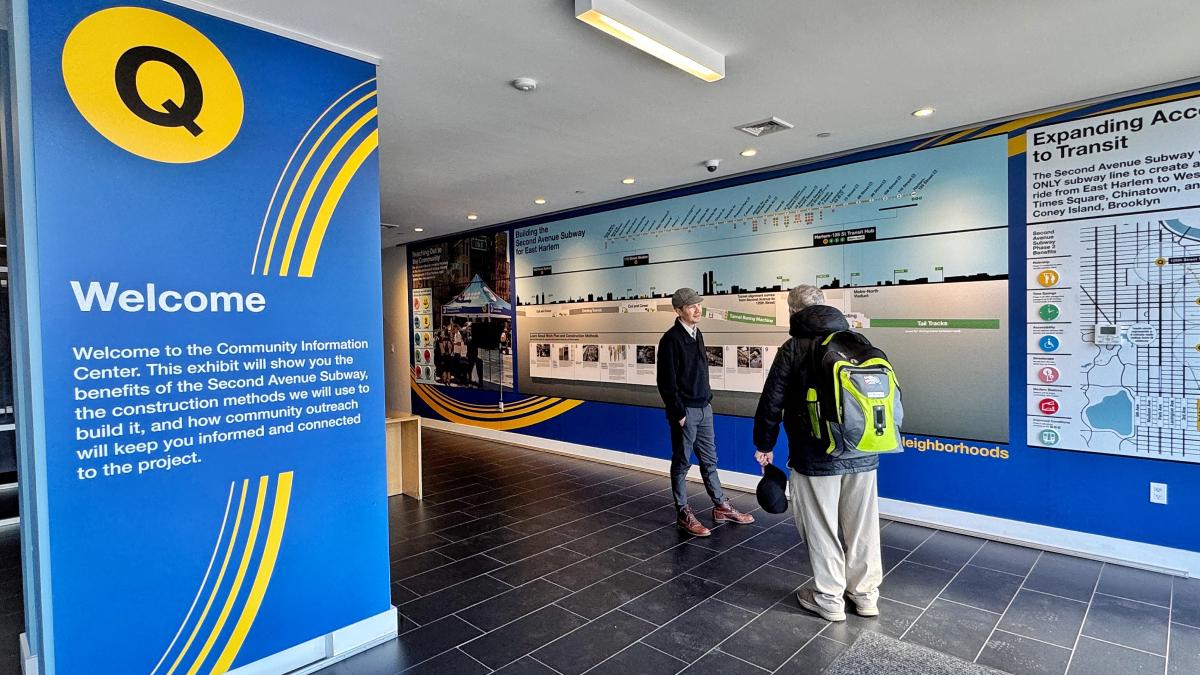 A project member explains the exhibit panels inside a community information center explaining the Second Avenue Subway project to a visitor. 