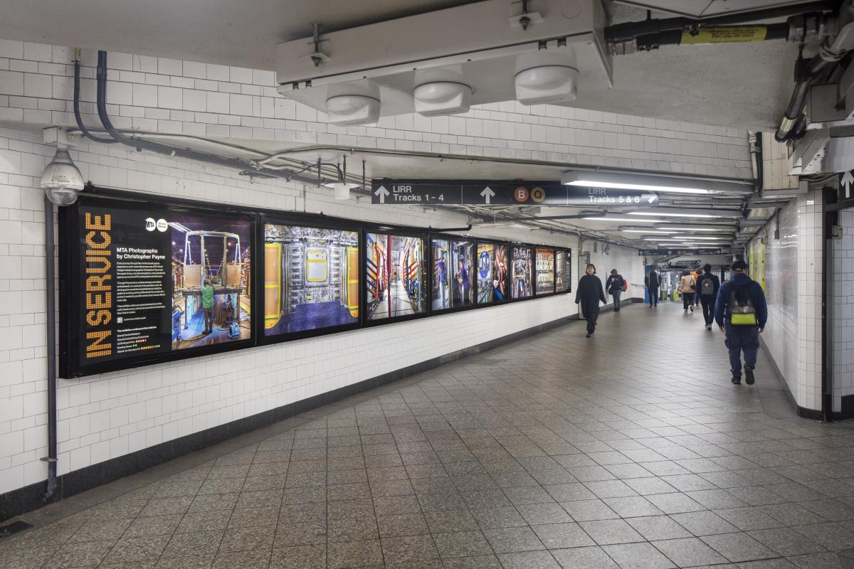 View of eight photography lightboxes in a subway transfer hallway.