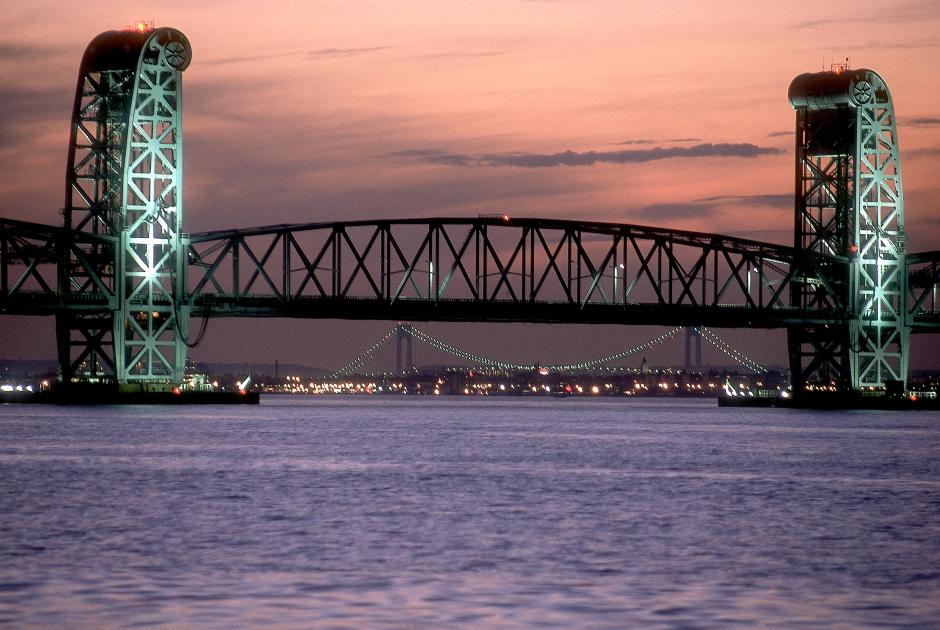 A bridge span stretches across lavender-colored water, with pink sky overhead.