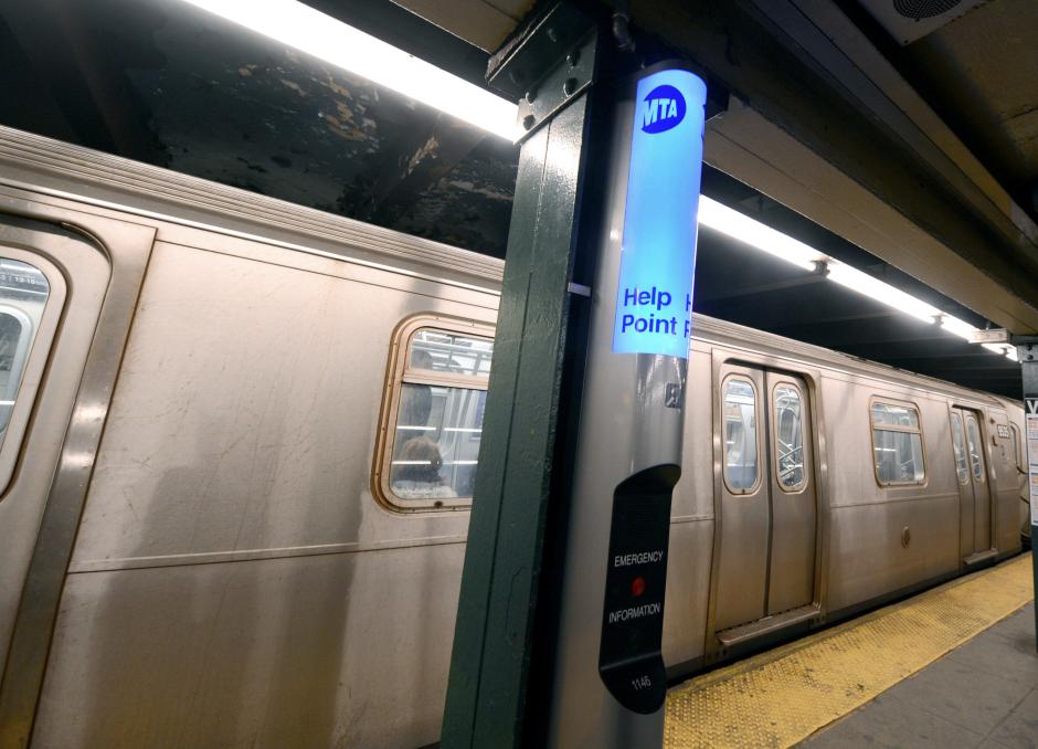 Help point on a column on a subway platform. A train is stopped at the station and the the doors are closed.
