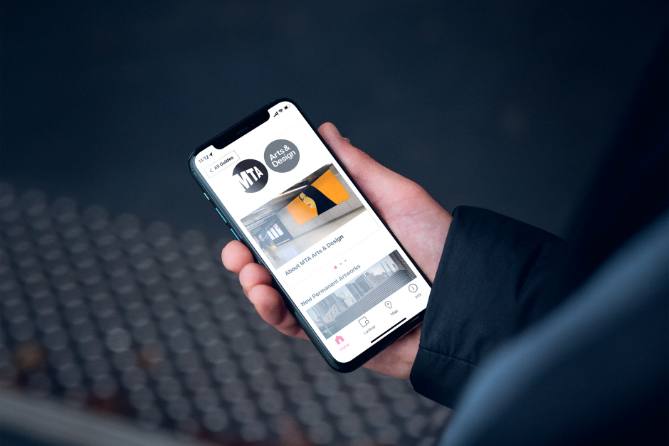 Figure holding a cell phone with a Bloomberg Connects digital guide on the screen.