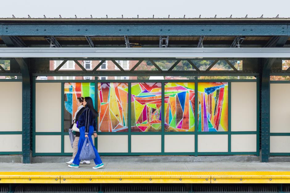 People standing in front of glass artwork installed in a station windscreen.