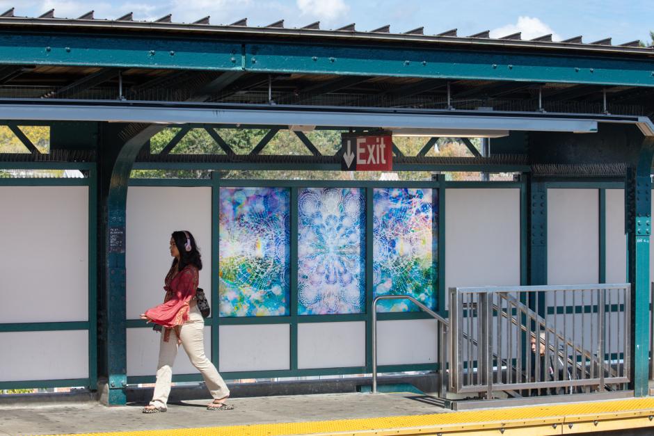 Person walking by glass artwork installed in a station windscreen.