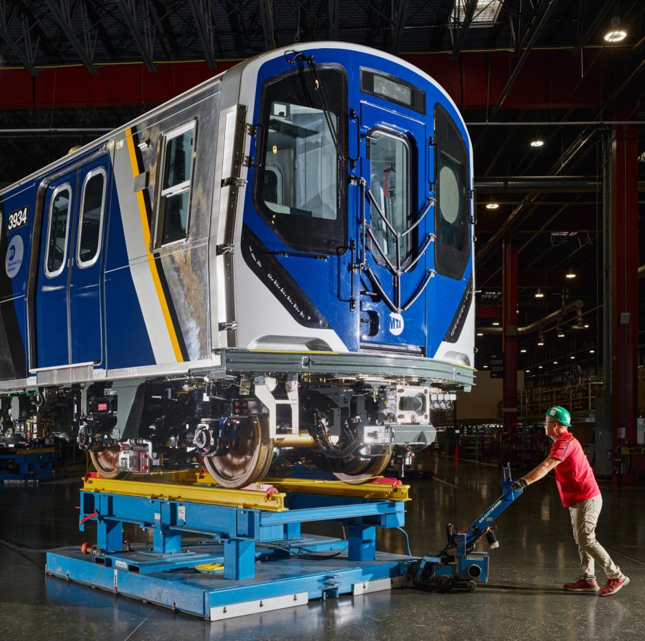 Employee moves completed MTA subway car on a specialized air pallet inside a maintenance facility.
