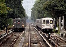 A vintage R9 and current R46 subway train on adjacent open tracks