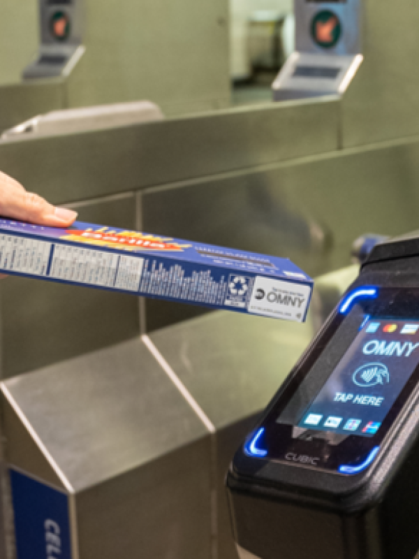 A customer tapping a turnstile using an OMNY sticker on a promotional product. 